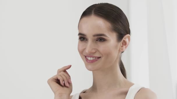 Cuidado de la piel. Hermosa sonriente mujer tocando la cara con los dedos — Vídeo de stock