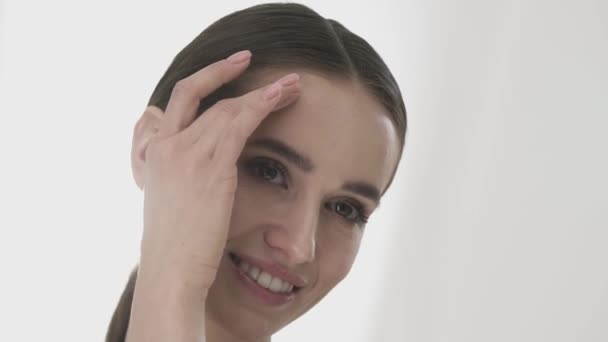 Zorg van de huid van het gezicht. Mooie vrouw aanraken van gezicht huid en glimlachen — Stockvideo