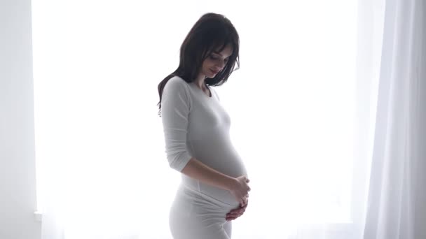 Zwangere vrouw aanraken baby buik in wit interieur — Stockvideo