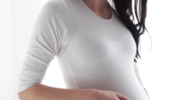 Schwangere berührt Babybauch im weißen Innenraum — Stockvideo