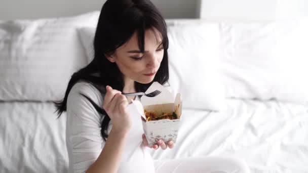 Έγκυος γυναίκα τρώει κινέζικο φαγητό στο σπίτι στο κρεβάτι — Αρχείο Βίντεο
