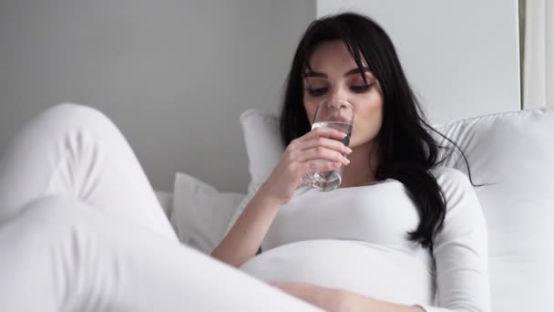 Πιες νερό. Έγκυος γυναίκα πόσιμο νερό από γυαλί στο σπίτι — Αρχείο Βίντεο
