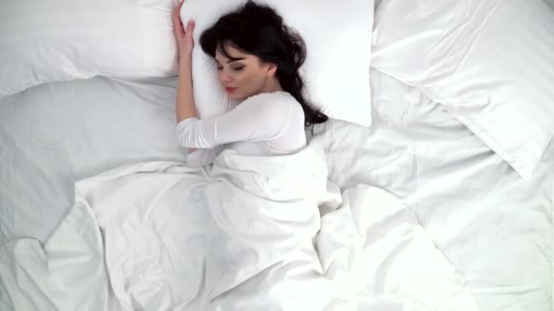 Nő alszik az ágyban, fehér ágyneművel, otthon