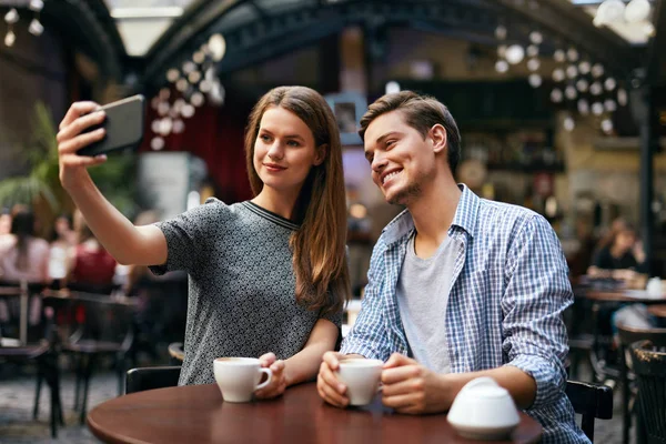 Pár fotografií na mobilním telefonu v Cafe — Stock fotografie