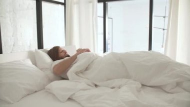 Işık yatak odası, beyaz keten ile yatakta uyuyan adam