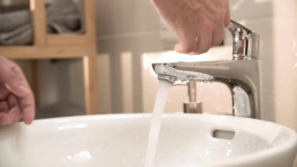 Fechar-se das mãos Ligue água corrente no dissipador no banheiro — Vídeo de Stock