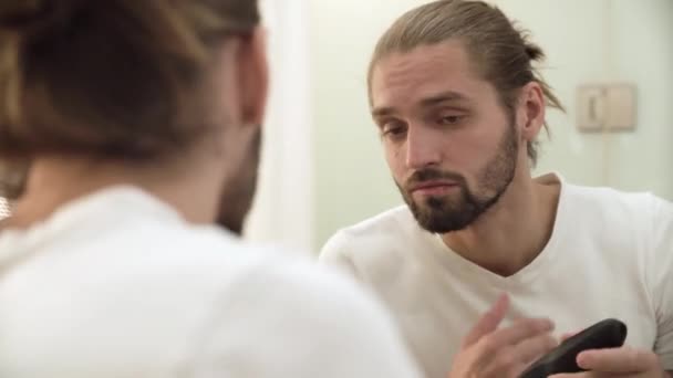 Uomo rasatura faccia con trimmer guardando nello specchio — Video Stock