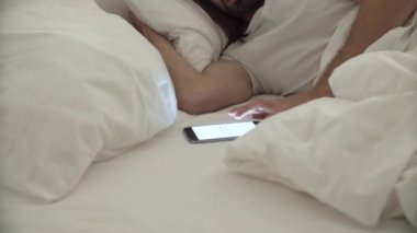 Uyandır. Telefonu alarmı ile yatakta uyuyan adam