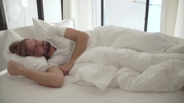 Спящий человек просыпается утром от шума снаружи — стоковое видео