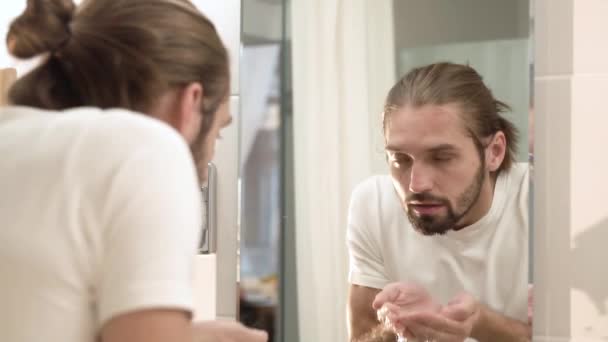 Uomo lavaggio faccia con acqua pulita e guardando specchio — Video Stock