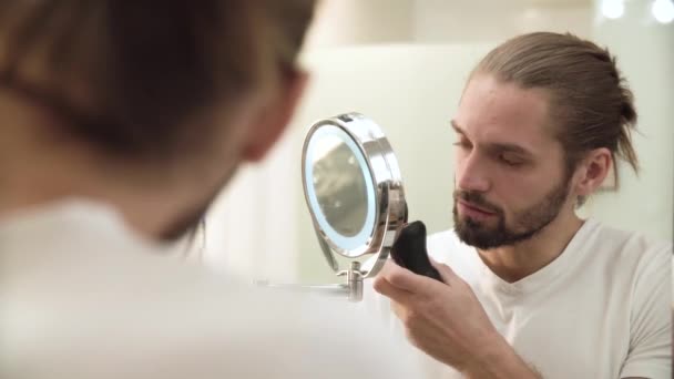 Man rakning ansikte med Trimmer tittar i spegeln — Stockvideo
