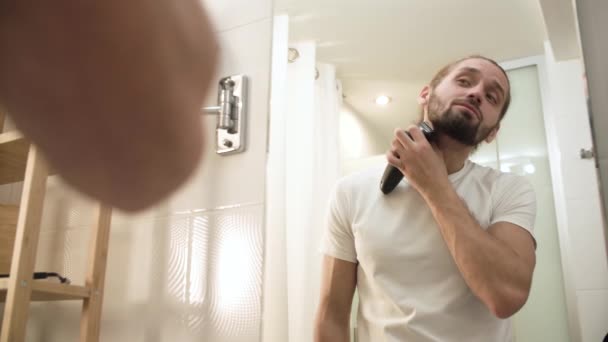 Uomo rasatura faccia con trimmer guardando nello specchio — Video Stock