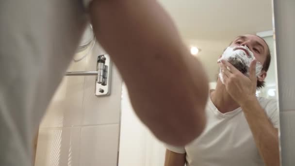 Man Applying Shaving Foam On Face Skin And Looking In Mirror — Stock Video