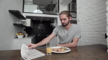 Gazete okuma ve evde mutfakta kahvaltı adam