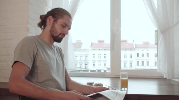 Frühstück. Mann liest Zeitung, trinkt Saft und isst Essen — Stockvideo