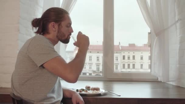 Ung Man dricker Juice och äter frukost hemma — Stockvideo