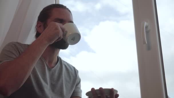 Man koffie drinken en genieten van het uitzicht uit raam — Stockvideo