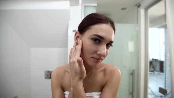 Женщина касается кожи лица в ванной комнате после душа — стоковое видео
