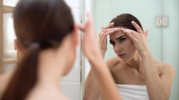 Проблема зі шкірою. Жінка дроблення пляма на обличчі і дивлячись у дзеркало — стокове відео