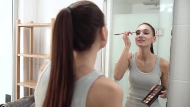 Makyaj. Kadın kaptırdın uygulamak ve aynaya bakıyor