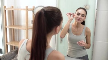 Güzellik makyaj. Kaşları banyo aynası fırçalama kadın