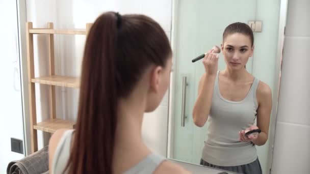 Maquillaje facial. Mujer usando polvo y mirando en espejo — Vídeos de Stock