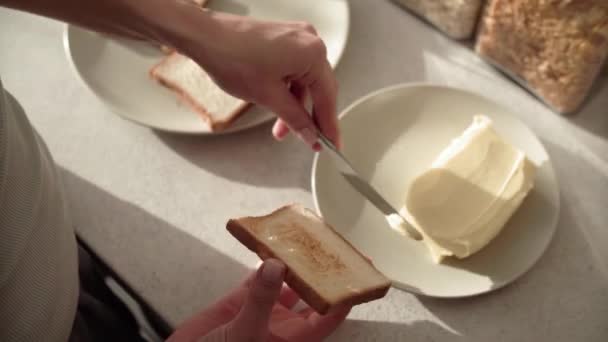 Brindis con mantequilla. Manos aplicando mantequilla en el primer plano del pan — Vídeos de Stock