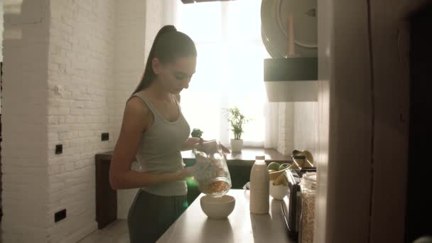 Nő főzés pehely és tej reggelit a világos konyha