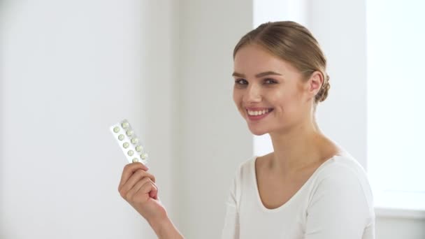 Здравоохранение. Женщина с волдырем таблеток улыбается перед камерой — стоковое видео