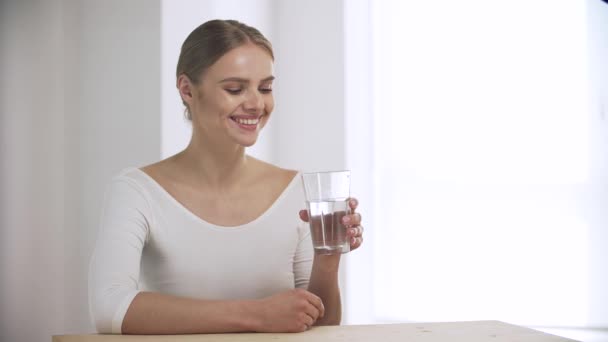 Frau trinkt Wasser aus Glas und blickt in Kamera — Stockvideo