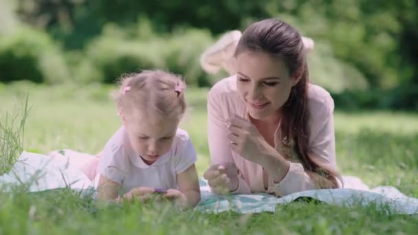 Rodinný čas. Matka a dcera odpočívají na přikrývce v parku — Stock video