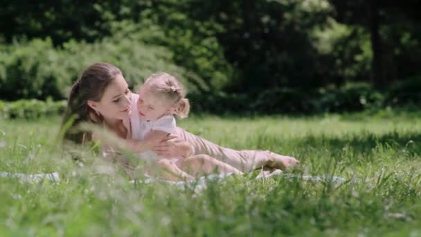 Aile zamanı. Anne ve kızı parkta battaniyenin üzerinde dinleniyor. — Stok video