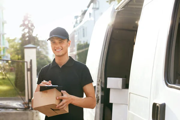 Υπηρεσία παράδοσης courier. Άνθρωπος με κουτί κοντά σε υπαίθρια αυτοκινήτου — Φωτογραφία Αρχείου