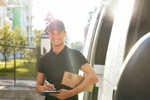 Υπηρεσία παράδοσης courier. Άνθρωπος με κουτί κοντά σε υπαίθρια αυτοκινήτου — Φωτογραφία Αρχείου