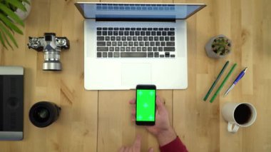 Tablo düz Lay çalışma yeşil ekranlı telefonu kullanan adam 