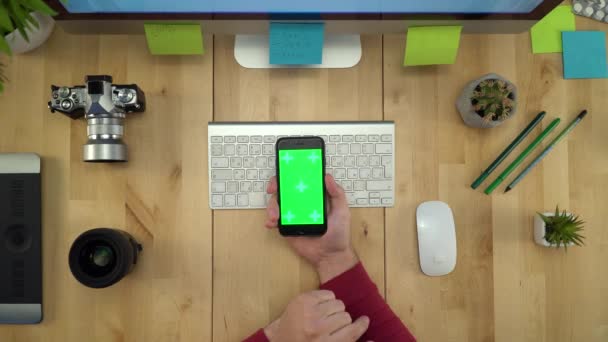 Colocación plana de las manos del hombre utilizando el teléfono con pantalla verde en el lugar de trabajo — Vídeos de Stock