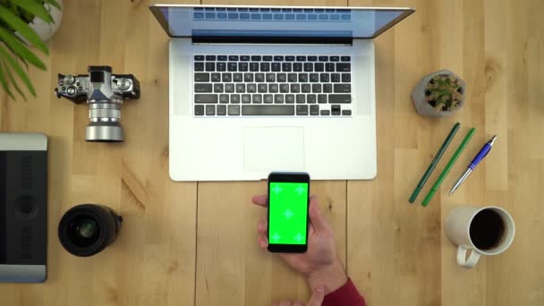 Плоская кладка рук человека с помощью телефона с зеленым экраном на рабочем месте — стоковое видео