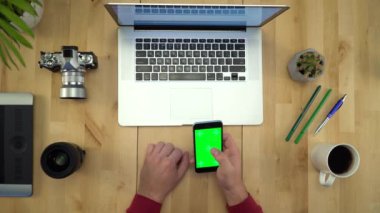 Tablo düz Lay çalışma yeşil ekranlı telefonu kullanan adam 