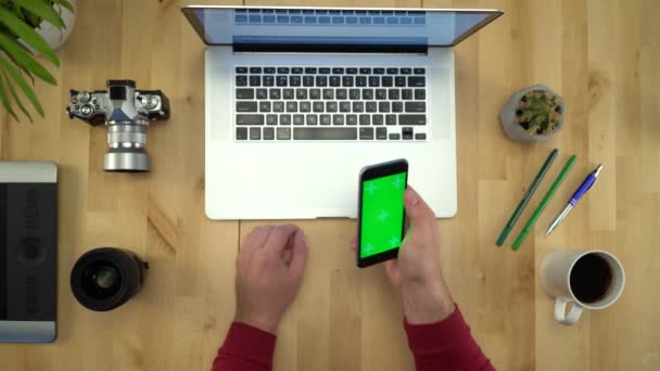 Плоская кладка рук человека с помощью телефона с зеленым экраном на рабочем месте — стоковое видео