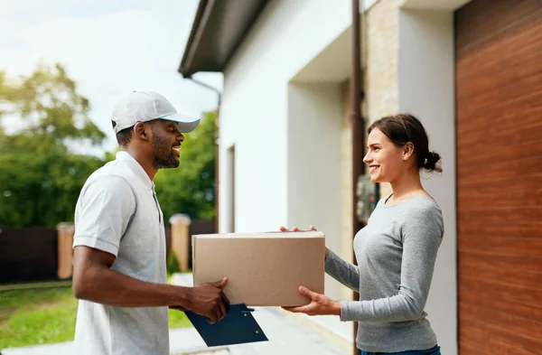 Kurierdienst. Mann bringt Paket zu Frau nach Hause — Stockfoto