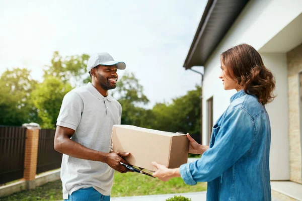 Paketdienste. Liefermann liefert Box an Frau aus — Stockfoto