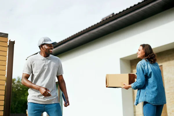 Consegna corriere. Consegnare pacchetto uomo alla donna a casa — Foto Stock