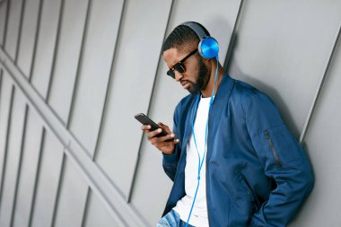 Moda ve müzik. Adam şehir telefon ve kulaklık ile