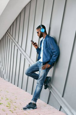Moda ve müzik. Adam şehir telefon ve kulaklık ile