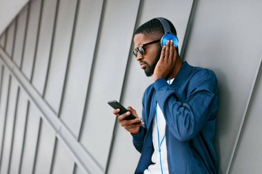 Moda ve müzik. Adam şehir telefon ve kulaklık ile