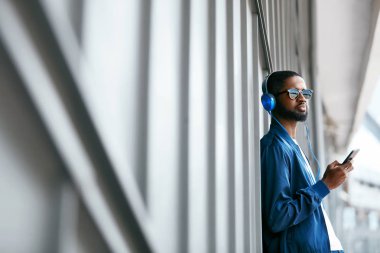 Moda ve müzik. Adam şehir telefon ve kulaklık ile