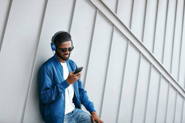 Moda ve müzik. Adam şehir telefon ve kulaklık ile