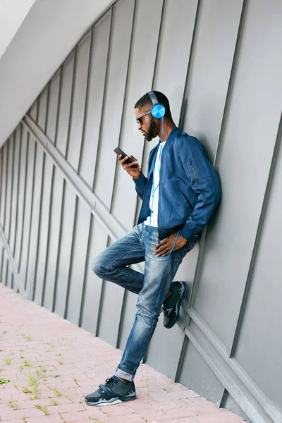 Móda a hudba. Muž se sluchátky a telefon v městě — Stock fotografie