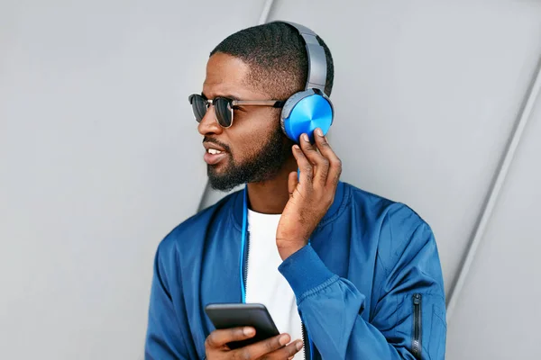 Musik hören. Mann mit Kopfhörer und Handy in Modekleidung — Stockfoto