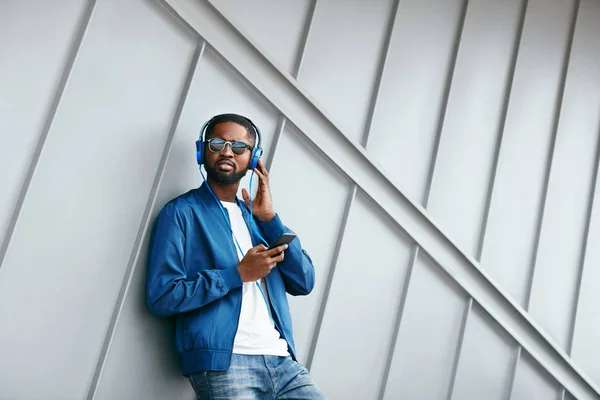 Mode und Musik. Mann mit Kopfhörer und Handy in der Stadt — Stockfoto